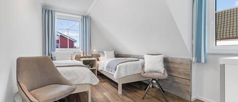 A modern, well-lit room with a bed, a chair, and a small table.