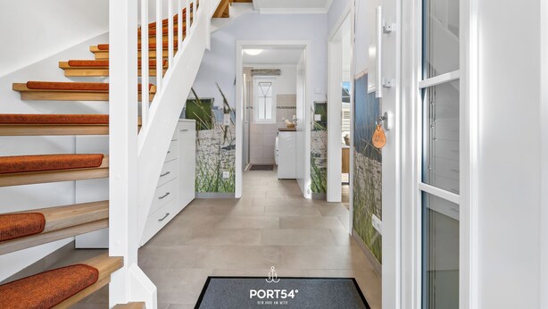 A modern interior with a staircase, white walls, and a hallway leading to a kitchen area. - Pier 12b - for 4 persons, parking space, quiet location, modern, cosy terrace (Büsum)