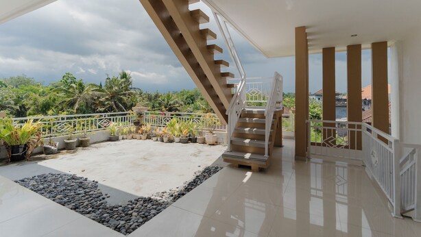 A spacious balcony with a white railing, a staircase, and potted plants. - Hotel Anyar Teges (Ubud)