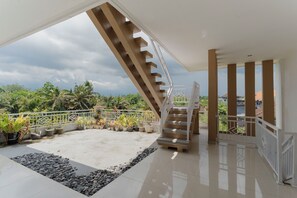 A spacious balcony with a white railing, a staircase, and potted plants. - Hotel Anyar Teges (Ubud)