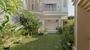 A two-story building with a balcony, a small garden with potted plants, and a clear pathway leading to the entrance. - Hotel Anyar Teges (Ubud)