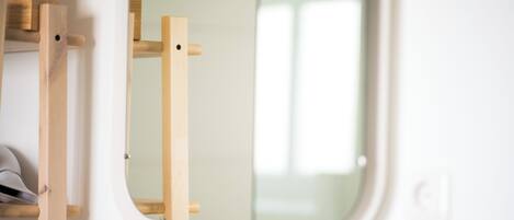 A white bathroom with a wooden shelf and a mirror.
