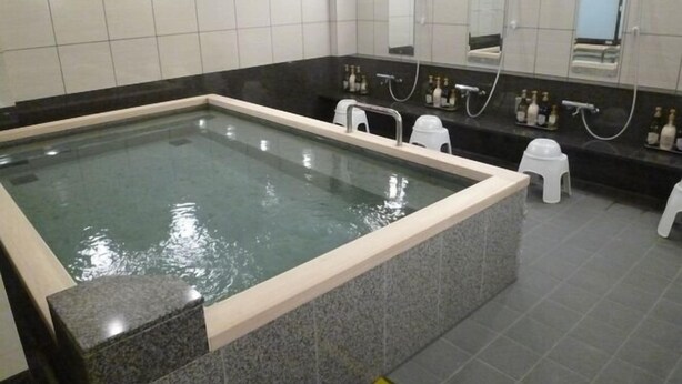 A rectangular pool with a tiled border, surrounded by a dark countertop and white stools. - Hotel Alpha-One Yonago (Yonago)