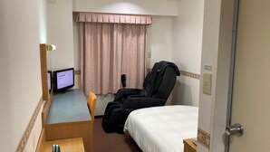 A hotel room with a bed, a massage chair, a desk with a computer, and a window with curtains. - Hotel Alpha-One Onomichi (Onomichi)