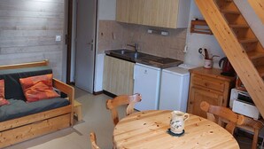 A compact kitchen with wooden cabinets, a built-in stove, and a small refrigerator.