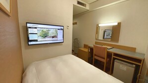 Camera d'albergo con un letto, una scrivania, una sedia, un piccolo frigorifero e una TV a parete che mostra il sito web dell'hotel.