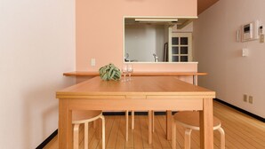 A modern kitchen with a wooden table, two chairs, and a hanging light fixture. - Dai37 Matsui Building (Sapporo)