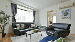 A modern living room with a sofa, armchair, coffee table, and a potted plant. - Dai37 Matsui Building (Sapporo)