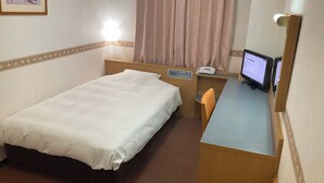 Una habitación de hotel con una cama individual, un escritorio con ordenador y un teléfono.