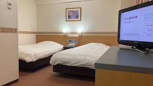 Habitación de hotel con dos camas, un escritorio, un televisor y un termostato instalado en la pared.