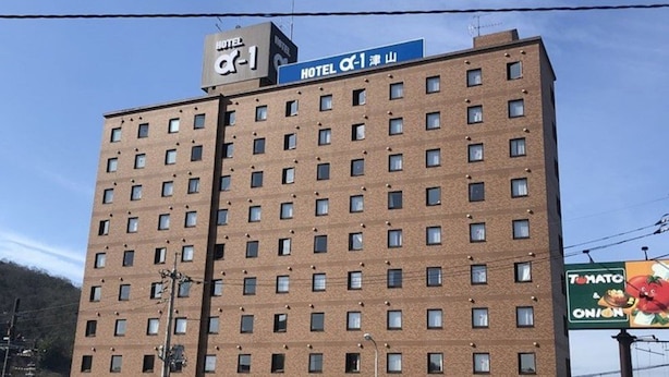 Un edificio de hotel de varios pisos con numerosas ventanas y un cartel que indica que es el Hotel Alpha-1.