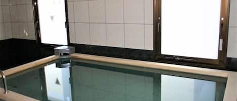 A swimming pool with a tiled wall and a glass barrier.