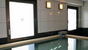 Una piscina interior moderna con paredes de vidrio transparente, suelo de baldosas y diseño minimalista.