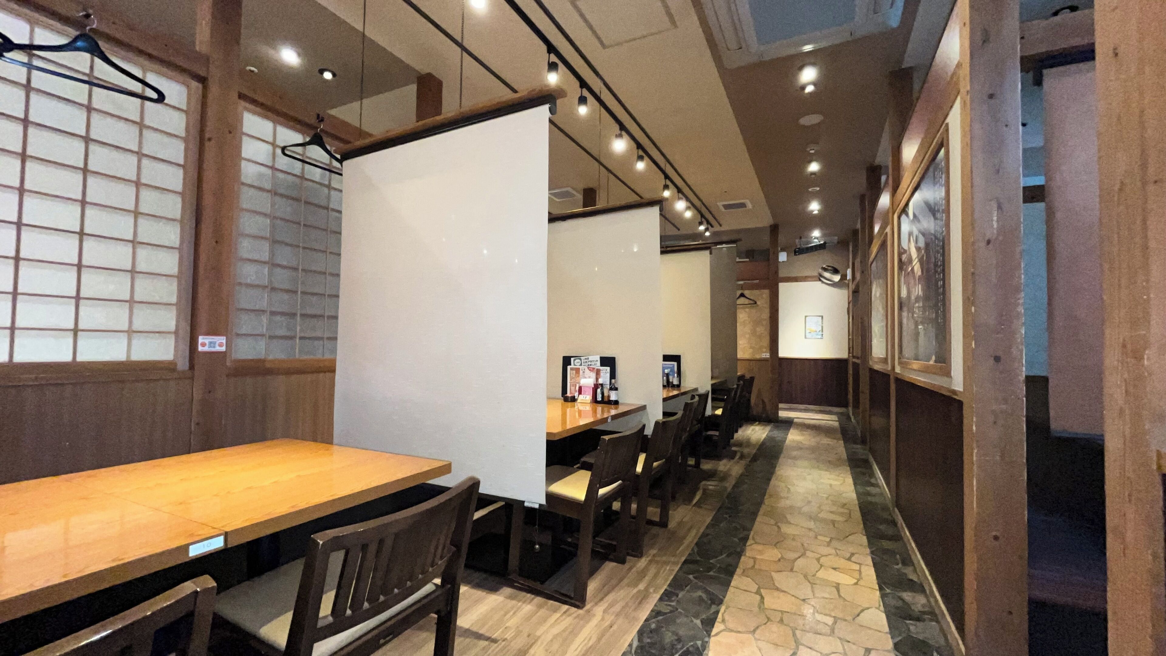A restaurant interior with wooden tables and chairs, a tiled floor, and a view of the street outside.