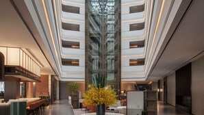 Un lobby de hotel moderno con un atrio central, zonas de estar y un bar.