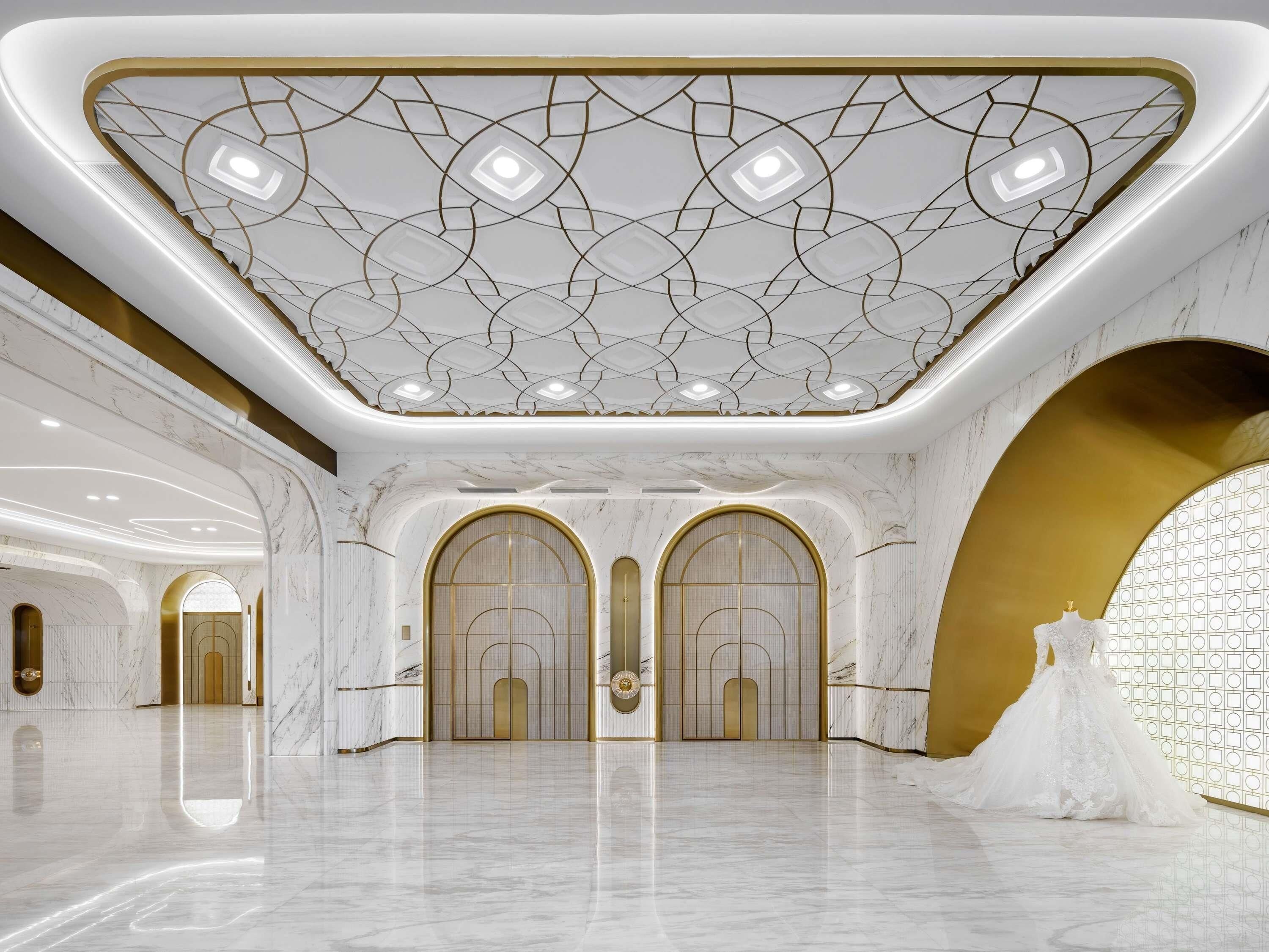 A spacious hall with marble floors, gold accents, and a patterned ceiling.