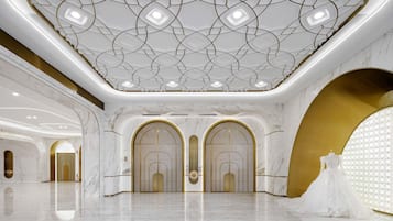 A spacious hall with marble floors, gold accents, and a patterned ceiling.