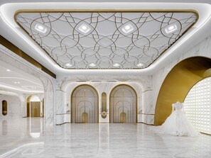 Un vaste hall doté de sols en marbre, d’éléments décoratifs dorés et d’un plafond orné de motifs.