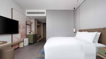 Una habitación de hotel moderna con una cama grande, un televisor de pantalla plana, un escritorio y un baño visible al fondo.