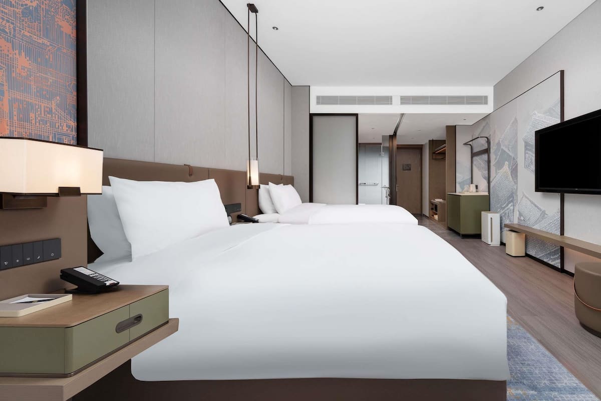 Een moderne hotelkamer met een groot bed, nachtkastjes, een televisie en een bureau.