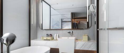 A modern bathroom with a bathtub, a large mirror, a vanity with a sink, and a shower area.
