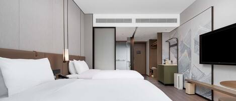 A modern hotel room with a large bed, a TV, a desk, and a walk-in closet.