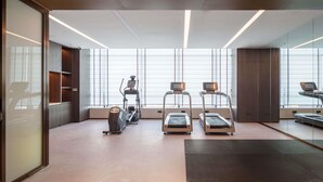 Une salle de sport moderne équipée de tapis de course, d’un vélo elliptique et d’un vélo d’appartement.