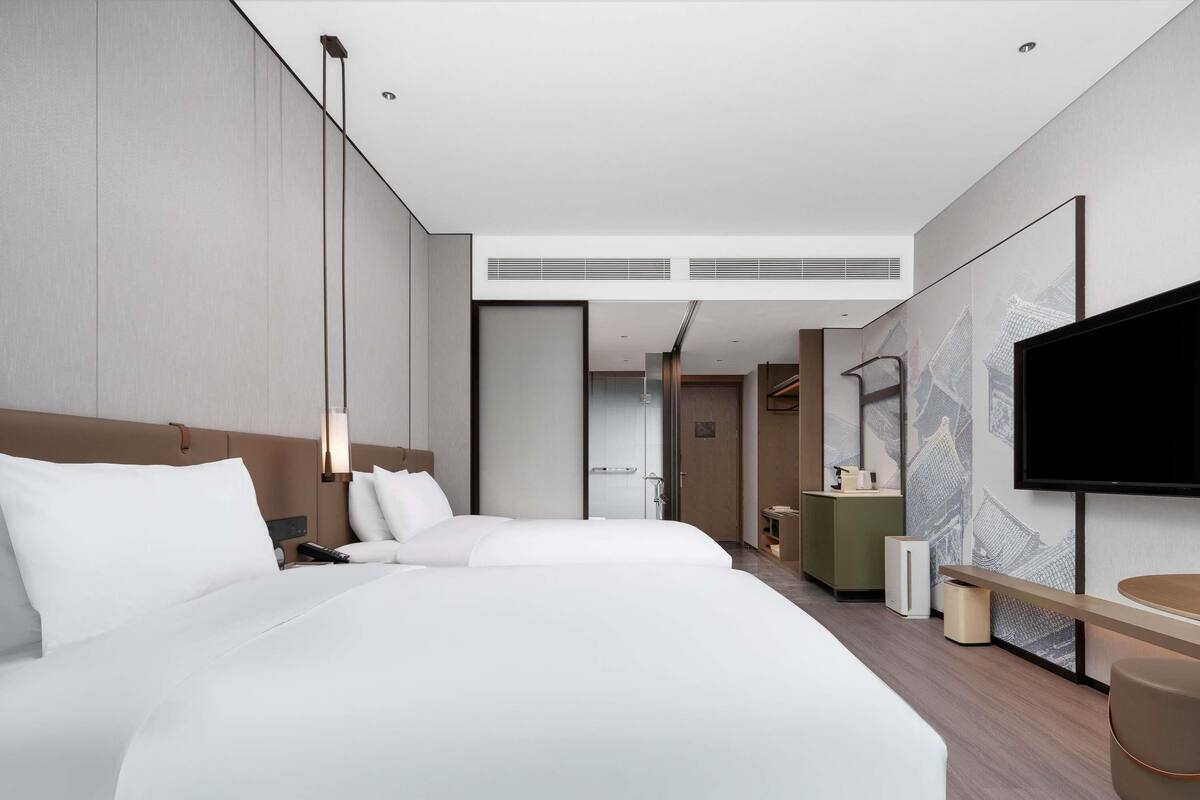 Een moderne hotelkamer met een groot bed, een televisie, een bureau en een inloopkast.