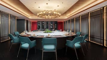 Un comedor moderno con una mesa redonda, sillas color turquesa y un candelabro.