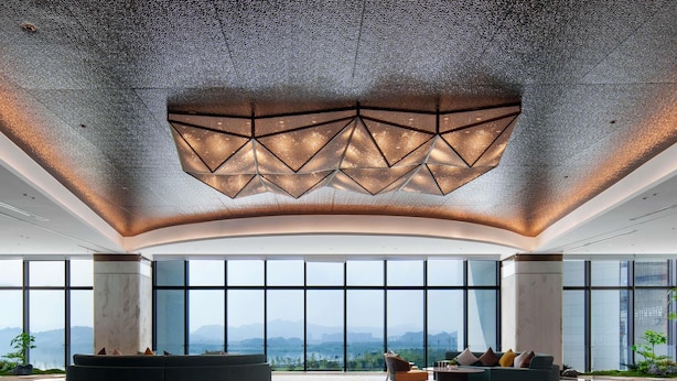 A spacious lobby with large windows, a reflective floor, and a unique ceiling design. - Grand Mercure Hangzhou Qingshan Lake (Hangzhou)