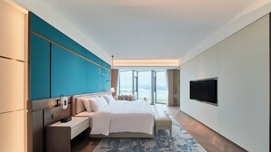 A modern hotel room with a large bed, bedside table, and a TV.