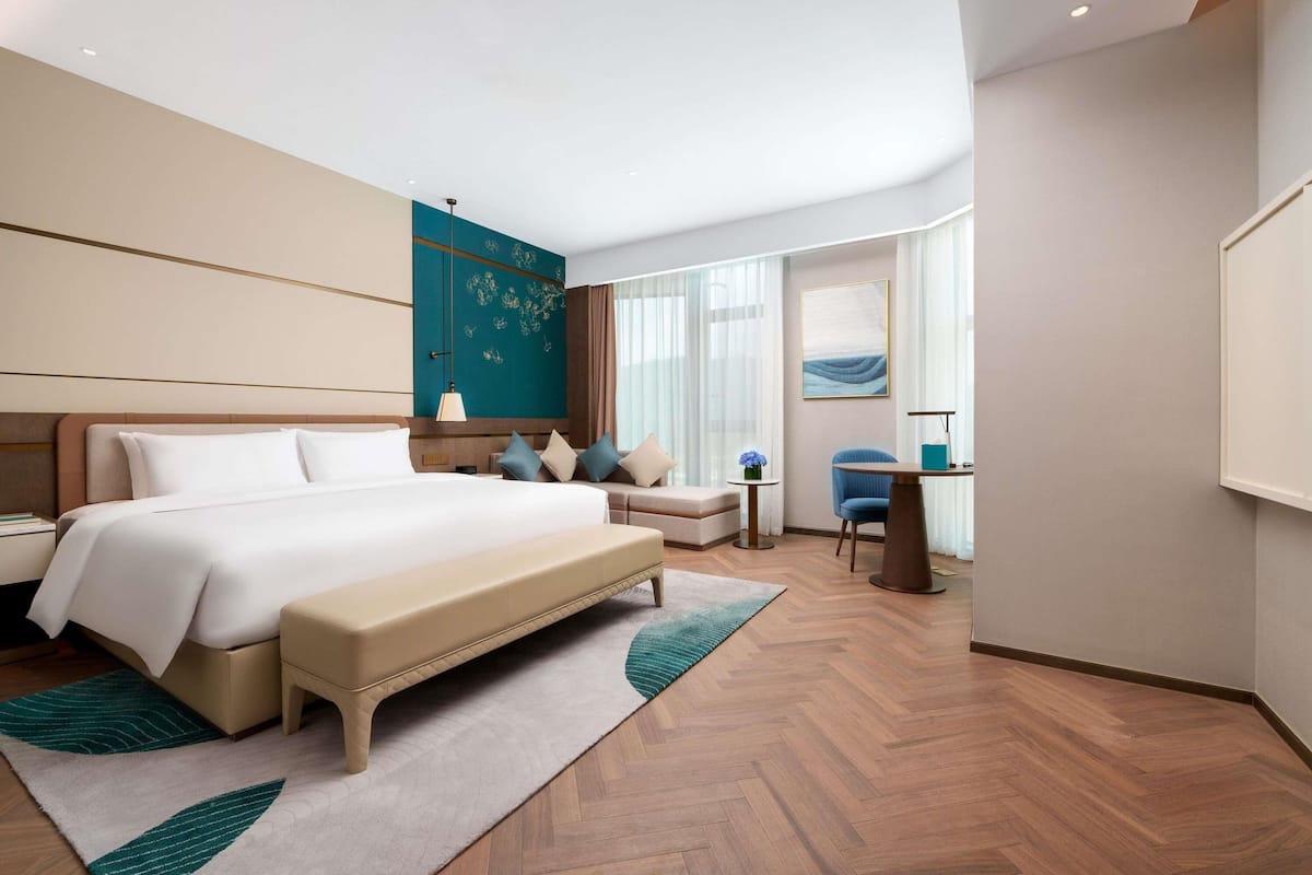 Una habitación de hotel moderna con una cama grande, un rincón de descanso y un escritorio.