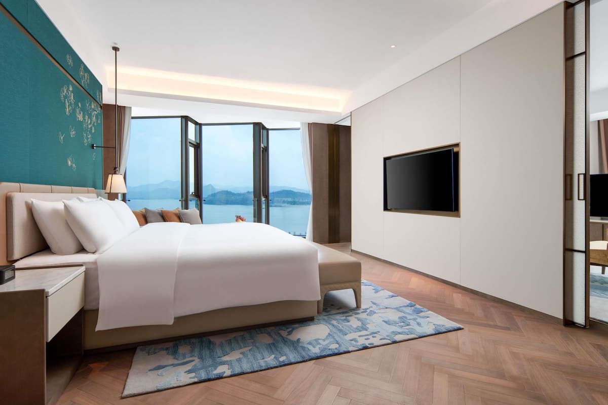 Una habitación de hotel moderna con una cama grande, un televisor de pantalla plana y vistas a un lago.