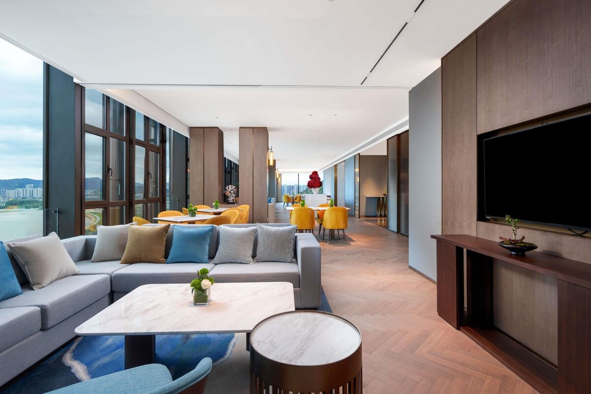 A modern lounge area with a sofa set, a coffee table, and a TV mounted on the wall.