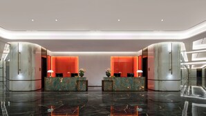 A modern lobby with marble reception desks, a glass ceiling, and a polished floor.