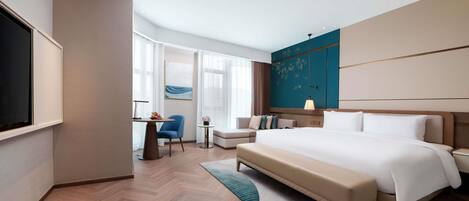 Una habitación de hotel moderna con una cama grande, un escritorio, una silla y un televisor.
