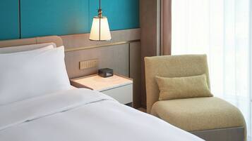 A hotel room with a bed, a nightstand, a lamp, and a chair.