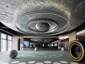 A gym with exercise equipment, a large exercise ball, and a circular design on the floor. - Grand Mercure Shenzhen Guangming (Shenzhen)