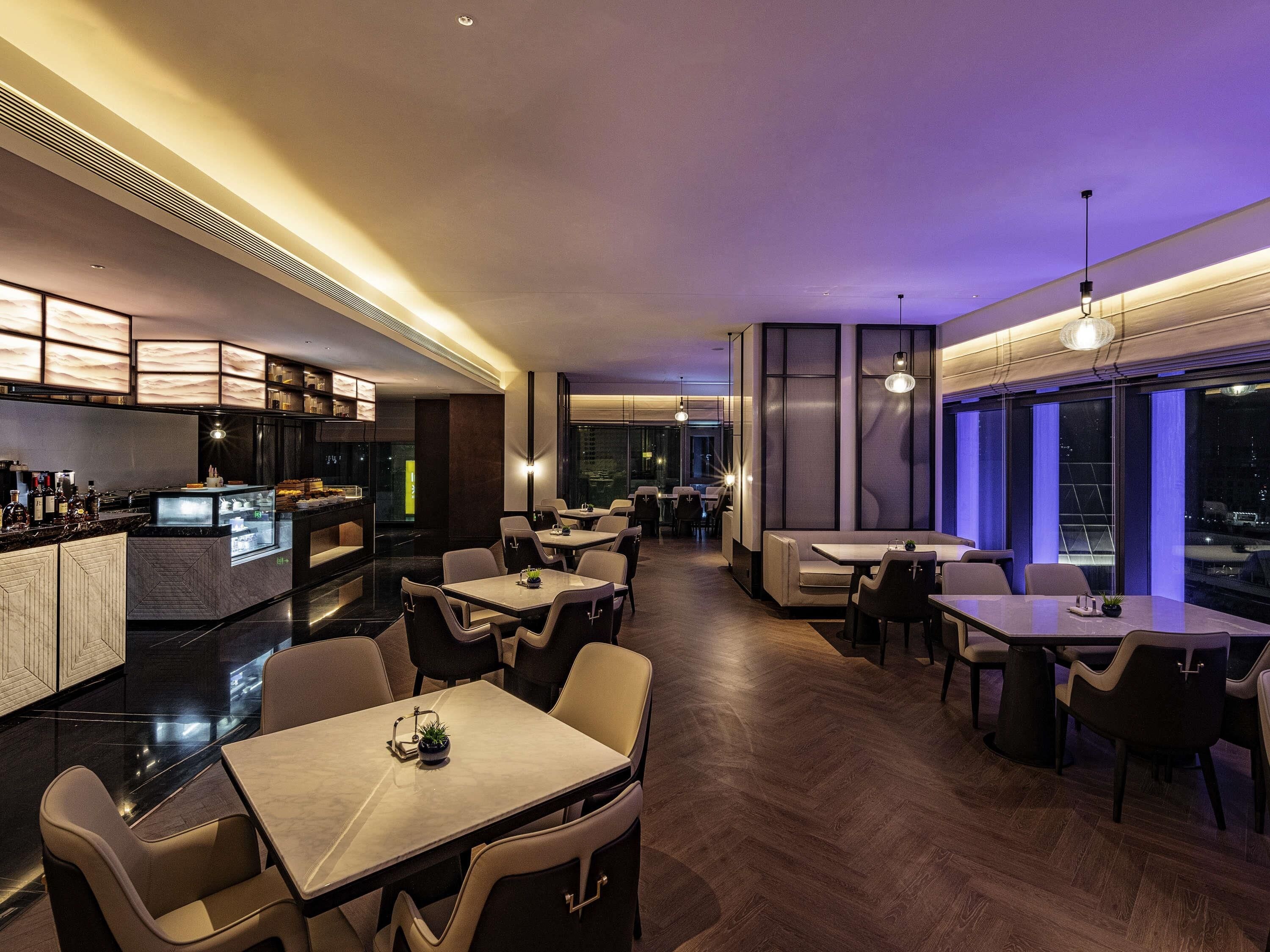 A modern restaurant with a bar area, dining tables, and chairs.