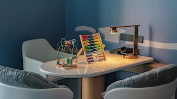 Children can play at a round table with a toy structure and lamp.