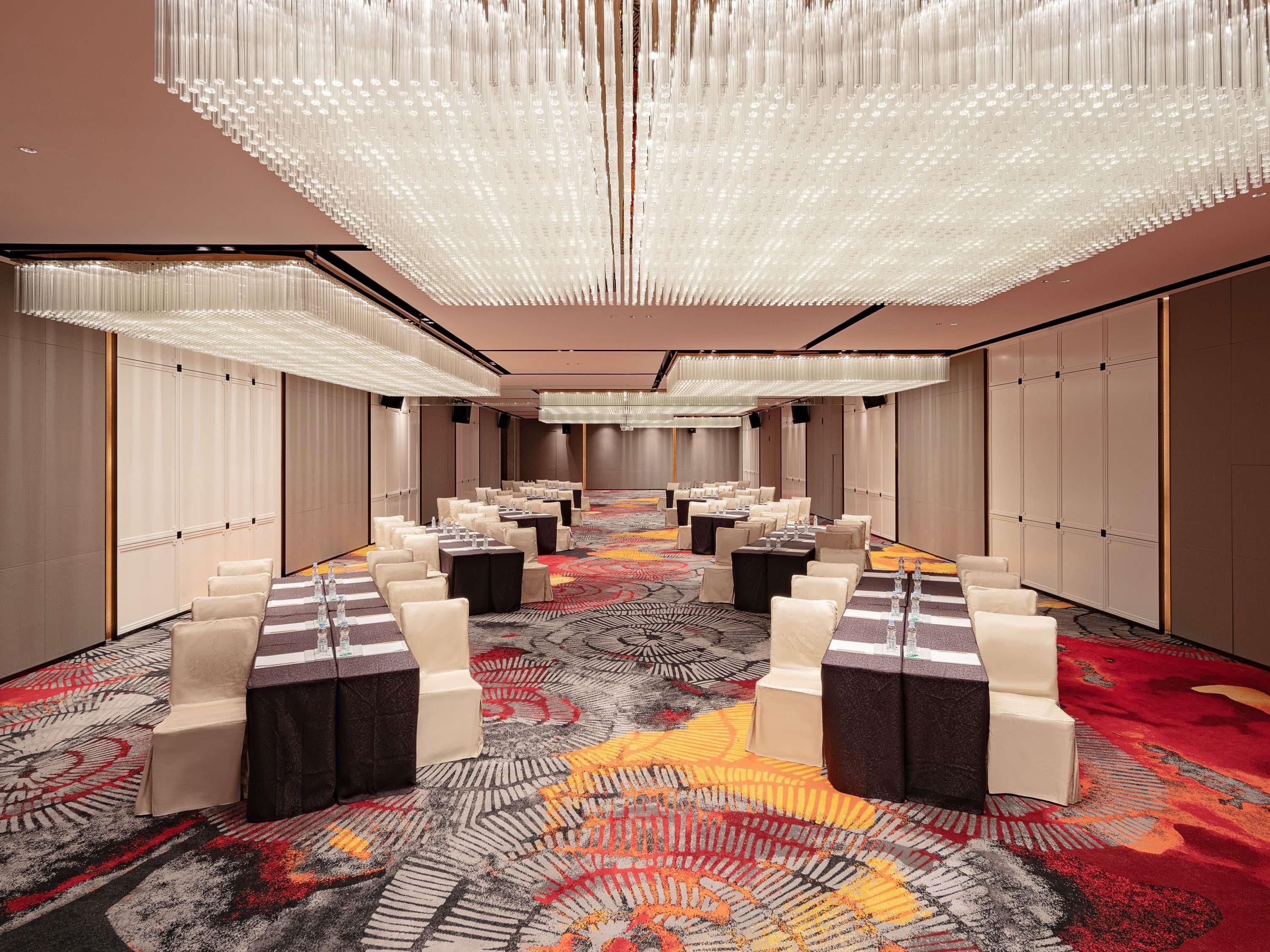 A conference room with rows of tables, chairs, and a patterned carpet.