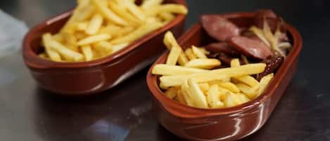Two ceramic bowls filled with French fries and sausages.