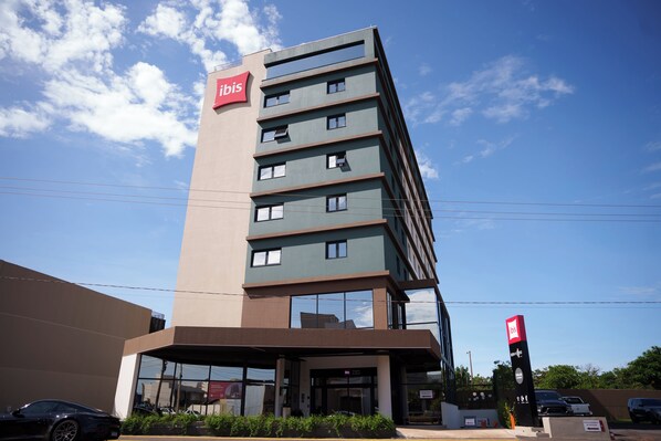 Un hôtel moderne, reconnaissable à son grand panneau « Ibis », avec de nombreux étages et une entrée en verre.