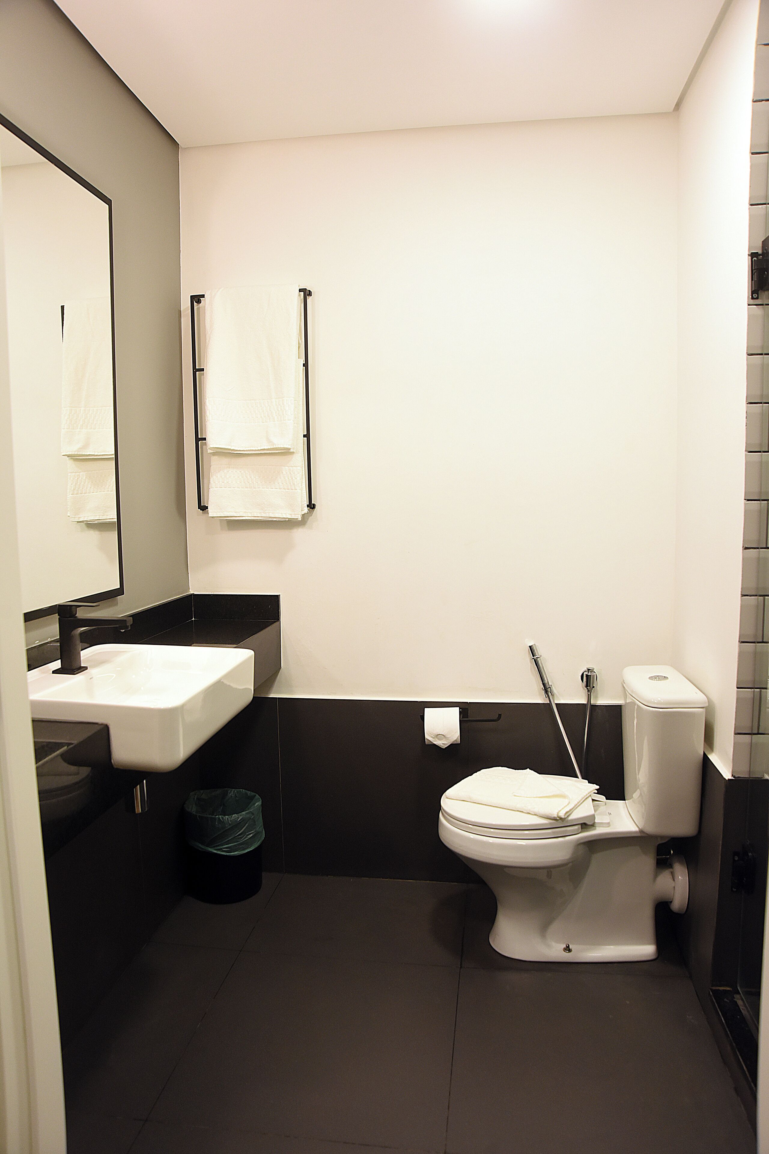 A modern bathroom with a white sink, black countertop, and a toilet with a bidet attachment.