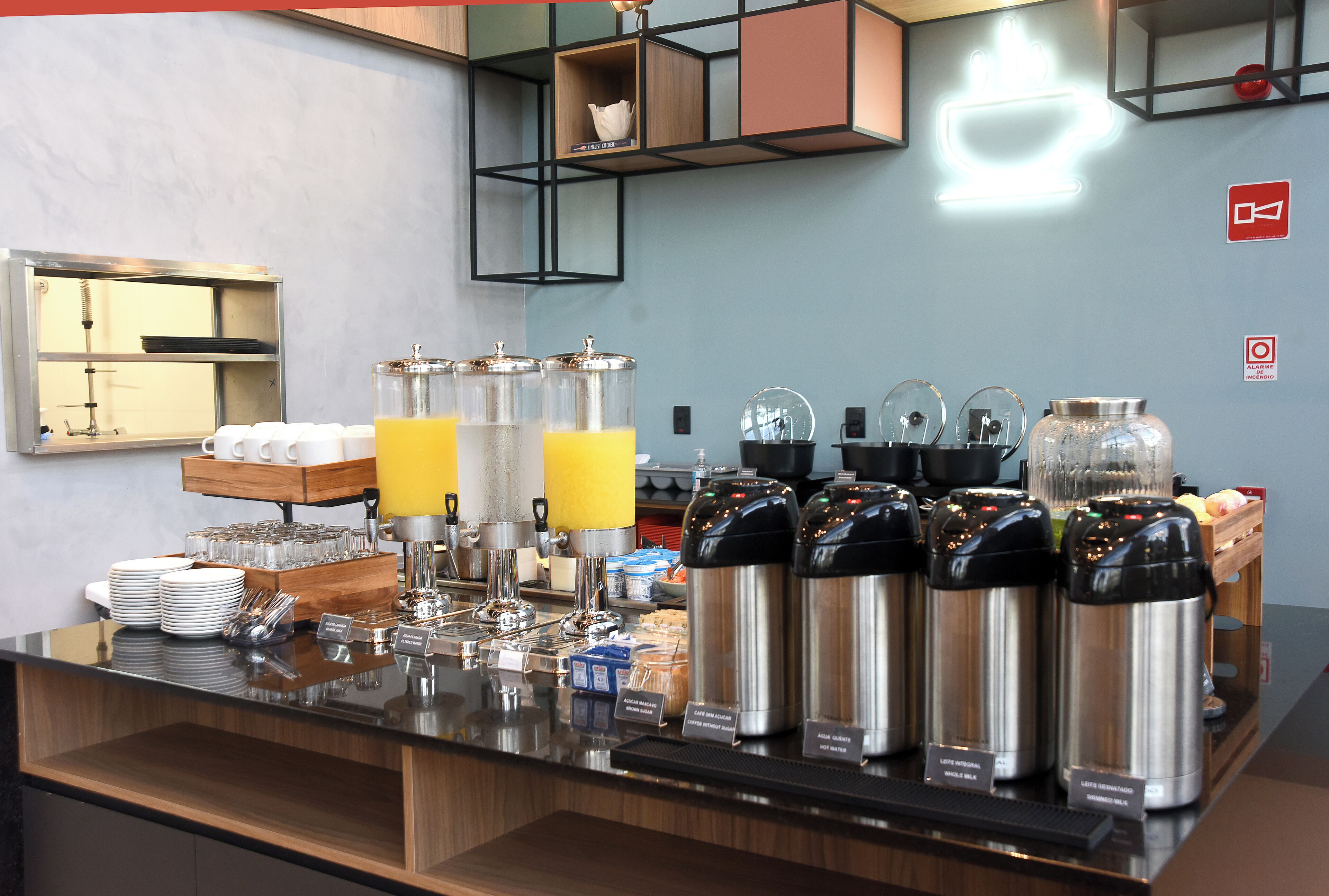 Una barra de desayuno con cafeteras, dispensadores de jugo y una variedad de alimentos para el desayuno.