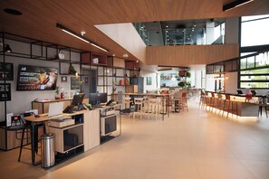 Un hall d’hôtel moderne comprenant un comptoir d’accueil, un espace salon et une grande fenêtre donnant sur un paysage agréable.