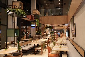 A modern restaurant with high ceilings, tiered seating, and indoor plants. - Ibis Tangara Da Serra (Tangará da Serra)