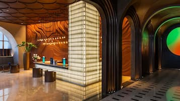 Eine moderne Lobby mit einer Rezeption, einer Sitzecke und einer großen beleuchteten Wand.