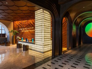 A modern lobby with a reception desk, seating area, and a large illuminated wall. - Mercure Garut City Center (Garut)