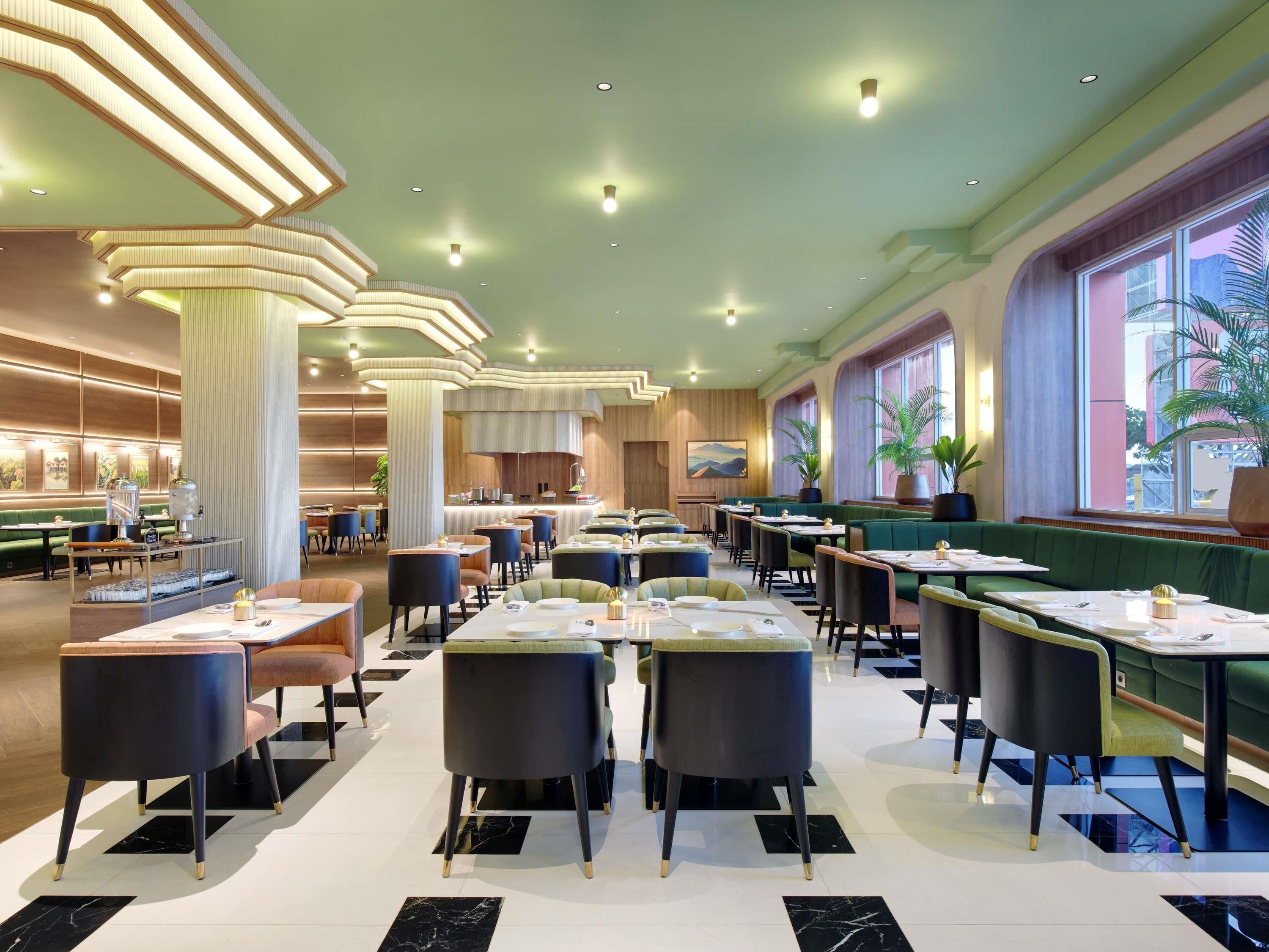 A spacious restaurant with high ceilings, modern lighting, and a view of the outdoors.
